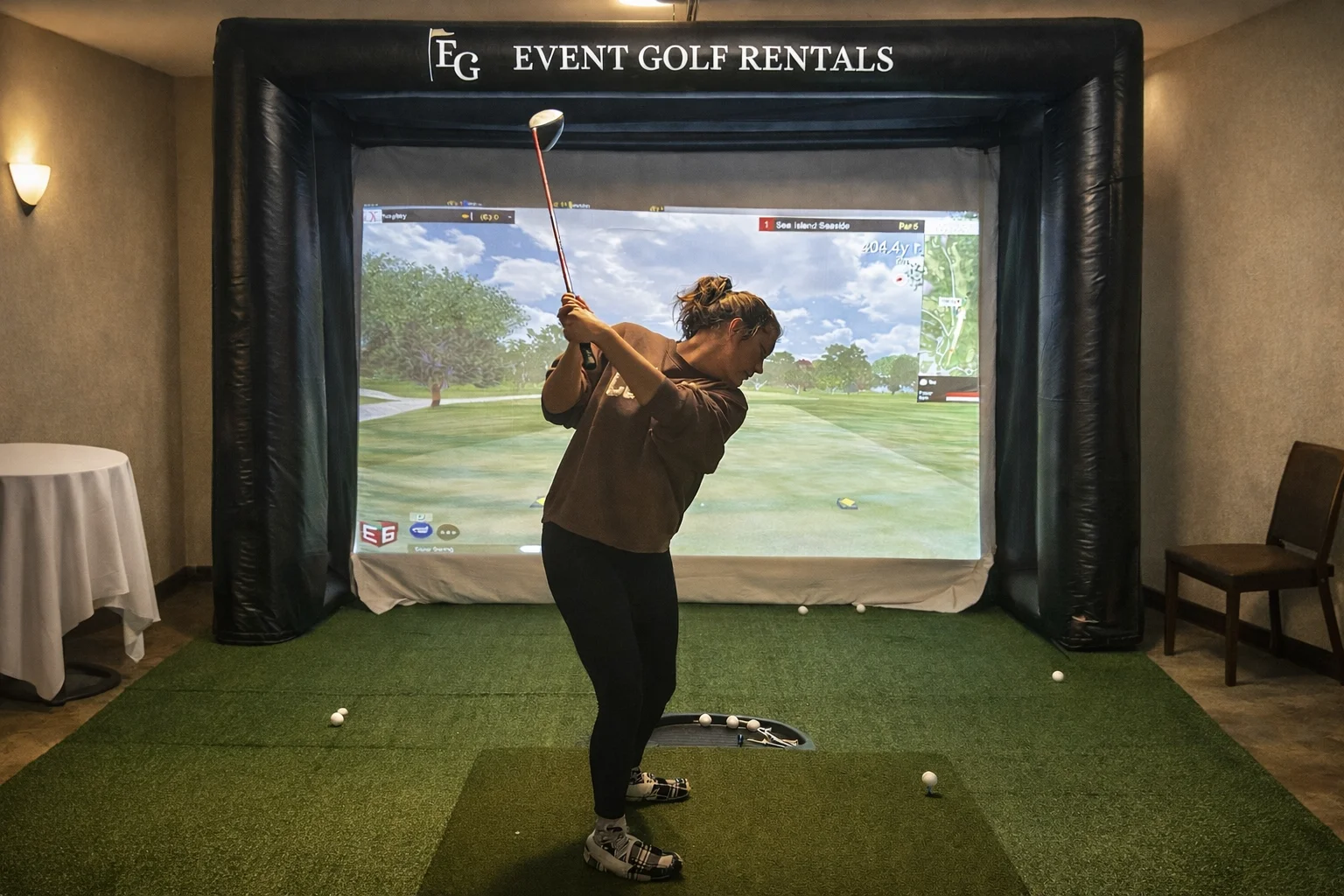 Woman swinging at golf simulator rental at wedding event in Northern Colorado